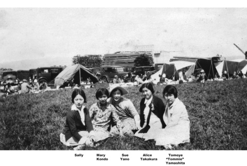 Five women sitting in field with tents and other picnickers in background (ddr-ajah-6-117)
