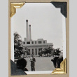 Man stands in front of building with smokestacks (ddr-densho-404-321)