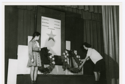 Woman adjusting wreaths at memorial service (ddr-densho-1007-347)