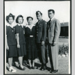 Photograph of five people, including an army soldier, posing in front of the Manzanar barracks (ddr-csujad-47-204)