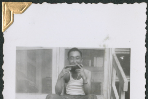 William Tsuchida sitting on steps eating watermelon (ddr-densho-434-227)
