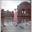 Woman in pink dress standing by pond by Palace of Fine Arts (ddr-densho-426-939)