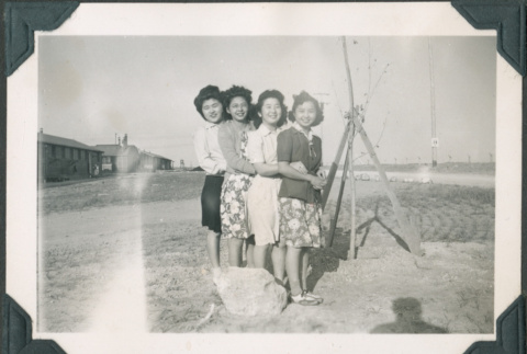 Four women in camp with barracks in background (ddr-densho-483-1100)