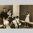 A young girl playing violin in front of her family (ddr-njpa-1-1472)