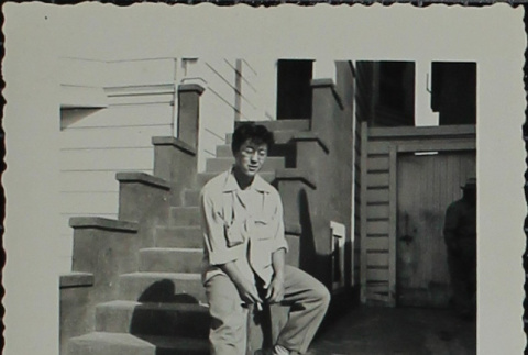 A young man sitting on front steps (ddr-densho-321-1184)