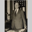 Judge posing in front of a flag, holding a gavel (ddr-njpa-2-792)