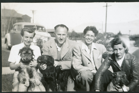 Photograph of people with dogs in front of a car and barracks (ddr-csujad-47-329)