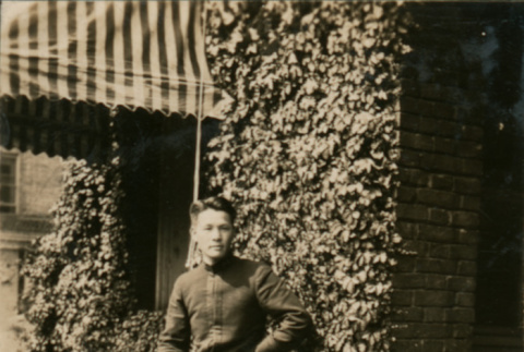 Young man seated near ivy-covered brick wall (ddr-densho-348-90)