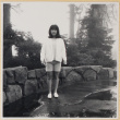 Girl standing by stone wall (ddr-densho-522-118)