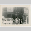 Photograph of three small boys standing in front of a bararcks with abandoned furniture (ddr-csujad-47-16)