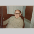 Man seated in chair smiling at camera (ddr-densho-426-2228)