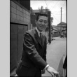 Man in suit with hand on car door (ddr-densho-426-2287)