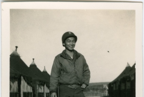 Man in military uniform standing by tents (ddr-densho-201-33)
