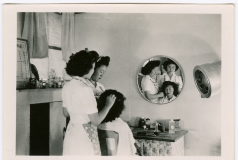 Two women styling another's hair (ddr-densho-475-429)