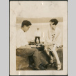 Couple sitting on a seawall with record player (ddr-densho-316-174)