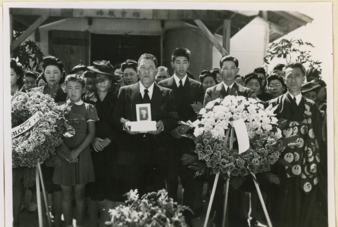 Mourner holds a portrait of Masao Kadonaga (ddr-densho-37-1389)
