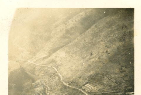Soldier sitting on a wall over a valley (ddr-densho-22-315)
