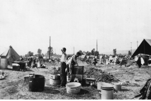 Men cleaning in field with tents (ddr-ajah-2-764)
