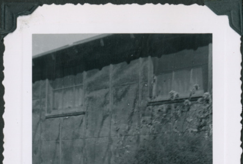 Two children on a bench with one in a baby walker outside barracks (ddr-densho-483-1096)
