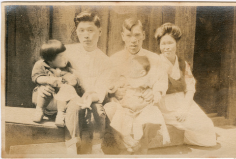 Two men and a woman with two small children seated outside building (ddr-densho-426-1899)