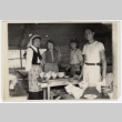 Four people standing around a table (ddr-densho-433-719)