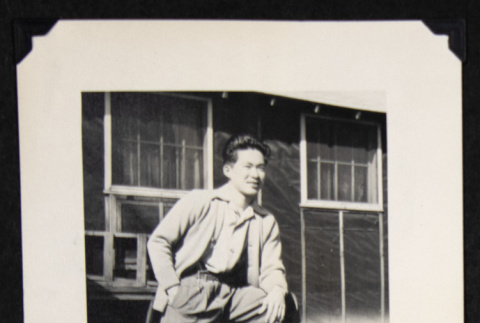 Gary Kikawa leaning on a stack of firewood (ddr-densho-542-730)