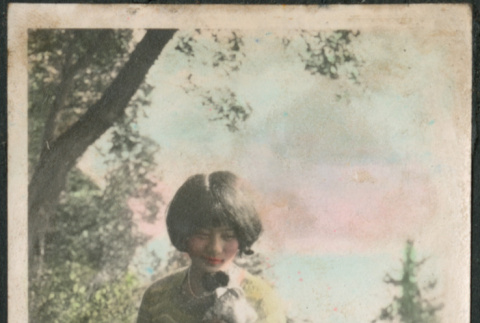 Woman sitting on railing holding stuffed toy (ddr-densho-523-7)