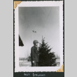 Man standing by tree and flag (ddr-densho-434-337)