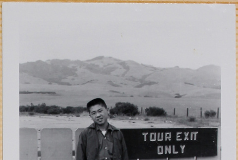William Shiomi by Tour Exit sign (ddr-densho-522-580)