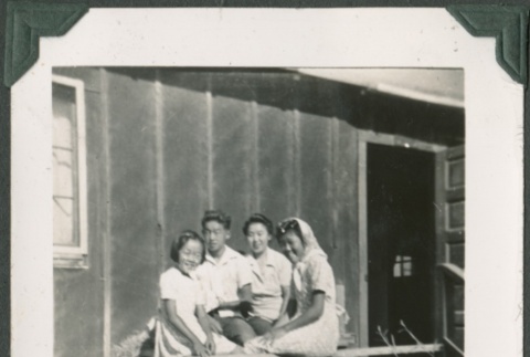 Group of four on porch in camp (ddr-densho-321-77)