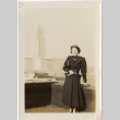 Tomoye (Nozawa) Takahashi standing with large building in background (ddr-densho-426-1779)
