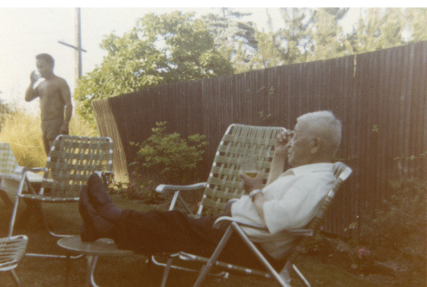 Fujitaro Kubota relaxing in Yano's backyard, George in background (ddr-densho-354-83)