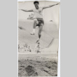 Man in track uniform doing long jump (ddr-densho-426-444)