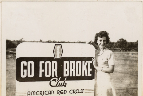 Woman standing by sign for Go For Broke Club, American Red Cross (ddr-densho-466-408)