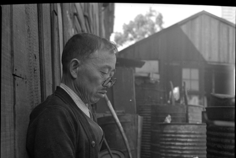 Man seated on bench reading a paper (ddr-densho-426-1746)