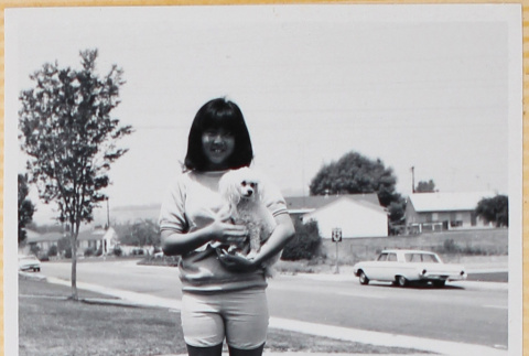 Girl standing on lawn holding dog (ddr-densho-522-116)