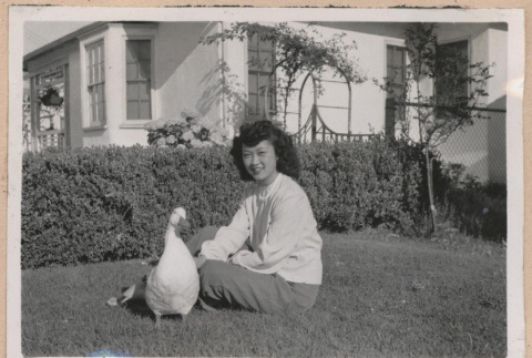 Woman sitting on a lawn with a duck (ddr-manz-10-96)