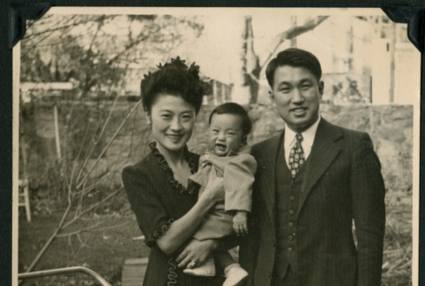 A mother, father, and baby pose behind a baby stroller. (ddr-densho-359-422)