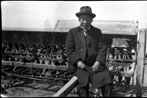 A man sits on agricultural machinery (ddr-densho-480-14)