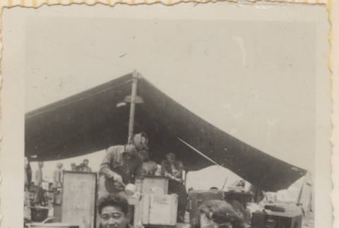 Man and woman in Red Cross uniform sitting outside mess tent (ddr-densho-466-373)