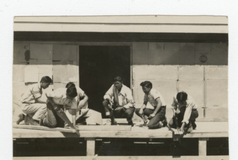 Nisei men with saws and hammers working on platform outside barrack (ddr-csujad-44-49)