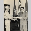 Two men shaking hands and exchanging a document (ddr-njpa-2-1122)
