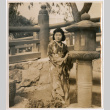 Tomoye (Nozawa) Takahashi in kimono standing by stone lantern (ddr-densho-426-1972)