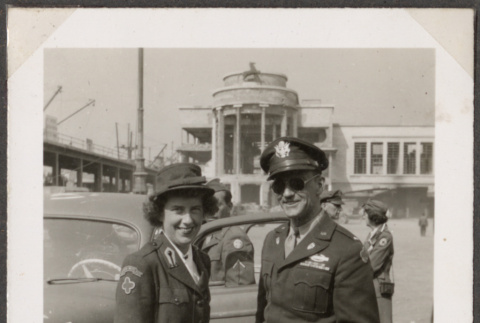 Women in Red Cross uniform standing with man in uniform next to car (ddr-densho-466-11)