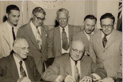 Ingram Stainback signing a document while other men look on (ddr-njpa-2-1195)