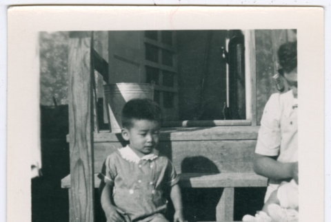 Boy sitting on barracks steps in Minidoka (ddr-densho-543-3)