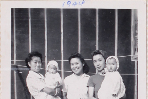 Three women standing outside barracks, two holding babies (ddr-densho-464-40)