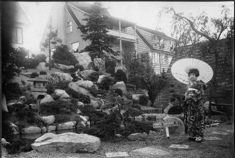 May Kubota in a kimono in front of a Kubota Gardening Company project (ddr-densho-354-119)
