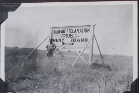 Man standing by large billboard (ddr-densho-467-26)