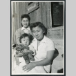 Photograph of two women an a young child posing in front of the infirmary at Cow Creek Camp in Death Valley (ddr-csujad-47-135)